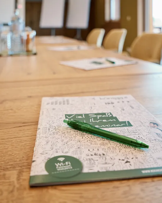 Blocco per seminari e penna verde su tavolo da conferenza in sala riunioni moderna